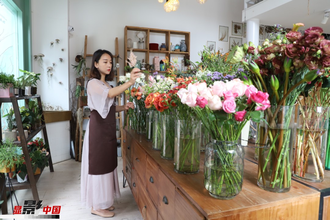 王黎媛是一名河南姑娘，在昆明念完大學(xué)后，就再也舍不下春城的藍天陽(yáng)光、青山碧水，更舍不下這里的四時(shí)繁花，于是就干脆留了下來(lái)，成了一名媒體人。2017年的時(shí)候又毅然辭去工作，創(chuàng  )業(yè)開(kāi)起了花店，成了都市里的一名“花房姑娘”。圖為王黎媛在自己的花店中整理鮮花。新華網(wǎng) 周亞平/攝 念新洪/文